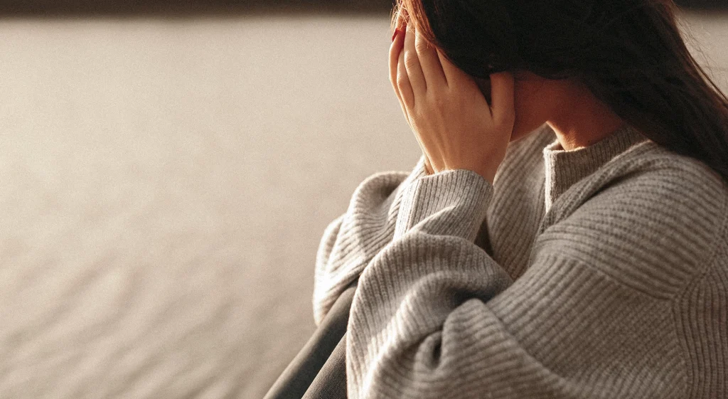 Imagen simbólica de una mujer tapándose el rostro, representando la tristeza y las secuelas emocionales de crecer en una infancia con madre narcisista.